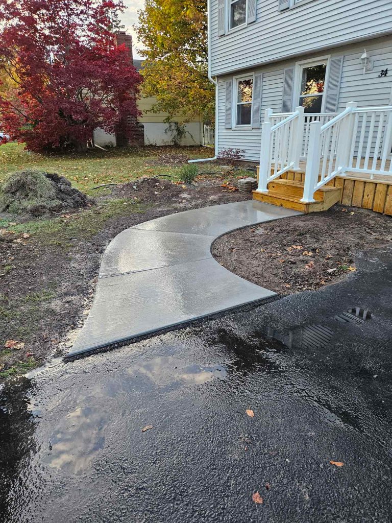 Newly poured concrete sidewalk connecting to asphalt driveway